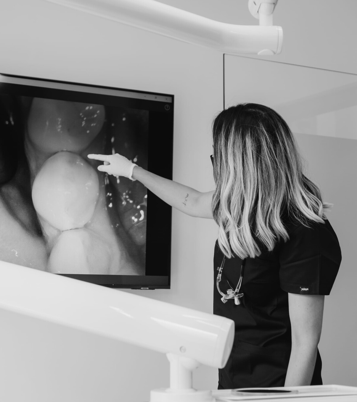 Lisa Kremer zeigt einer Patientin etwas auf einem Bildschirm mit der Aufnahme einer Intraoralkamera.
