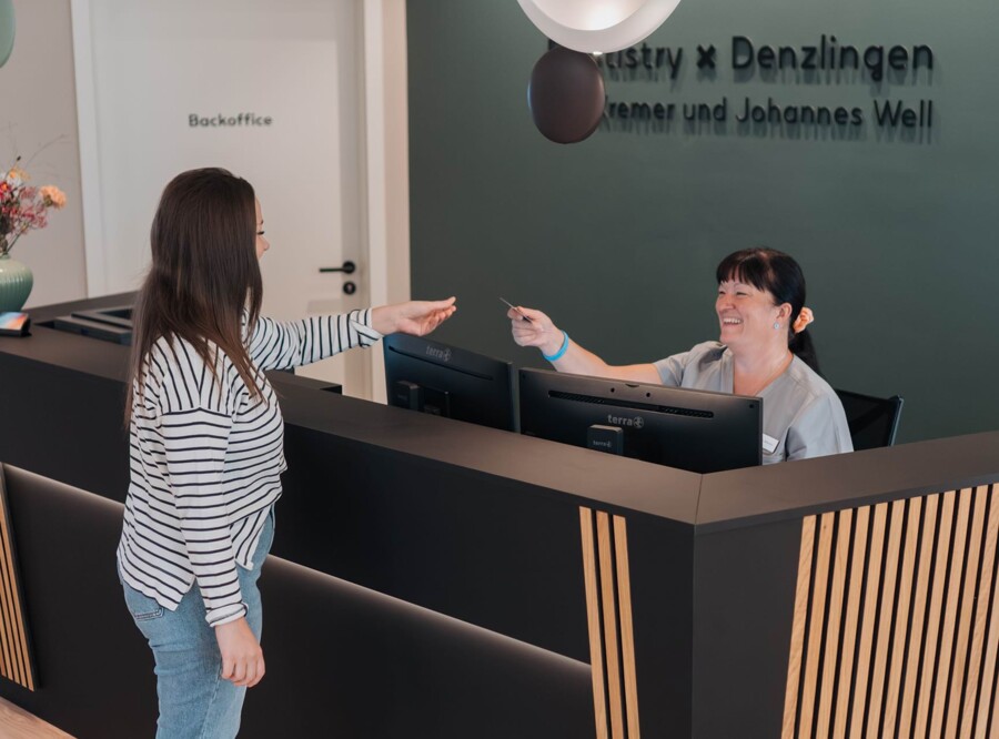 Patientin wird an der Rezeption freundlich empfangen.