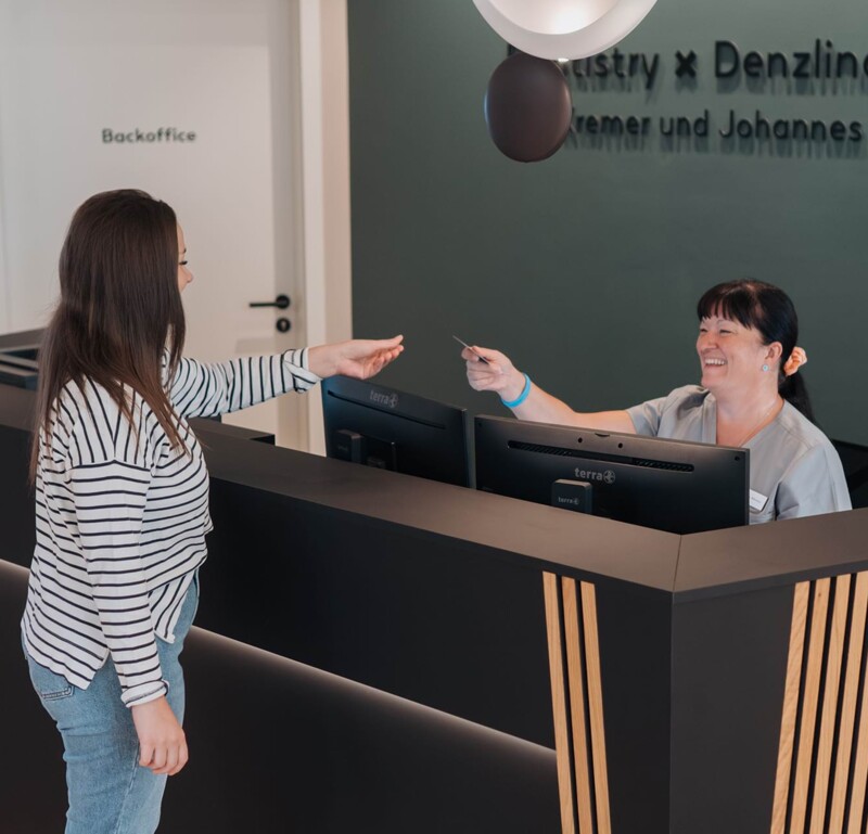 Patientin bekommt an der Rezeption eine Terminkarte überreicht.