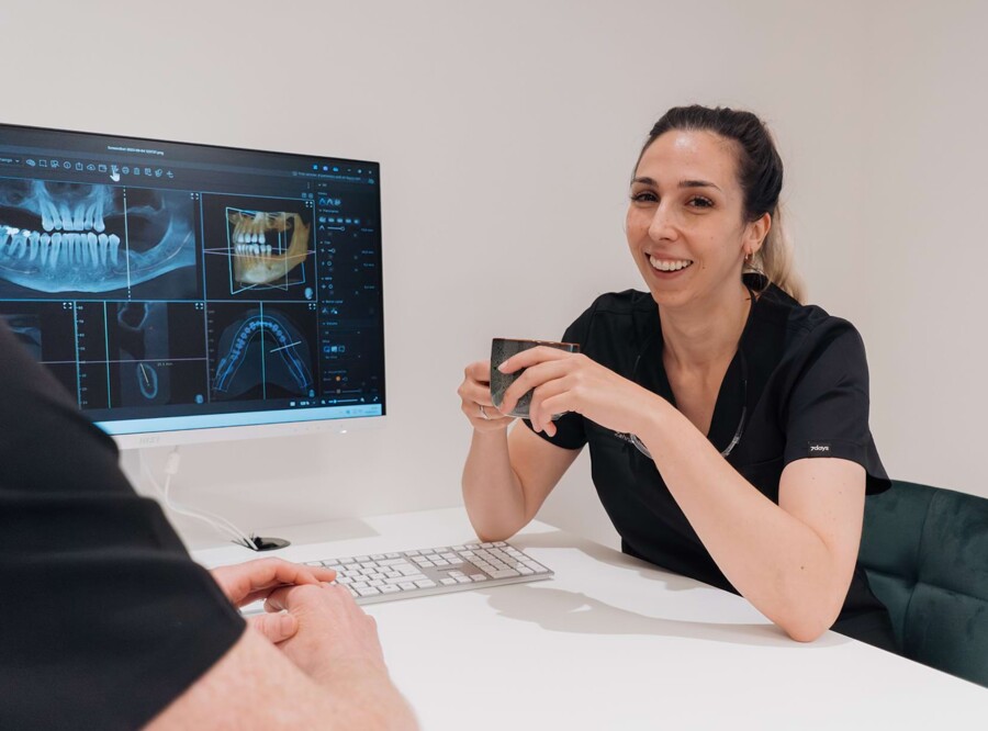 Lisa Kremer im Beratungszimmer. Im Hintergrund ist ein Desktop mit einem Intraoralscan darauf zu sehen.