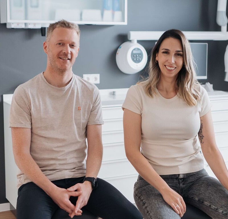 Johannes Well (links) und Lisa Kremer (rechts) sitzen im hellen Behandlungszimmer.